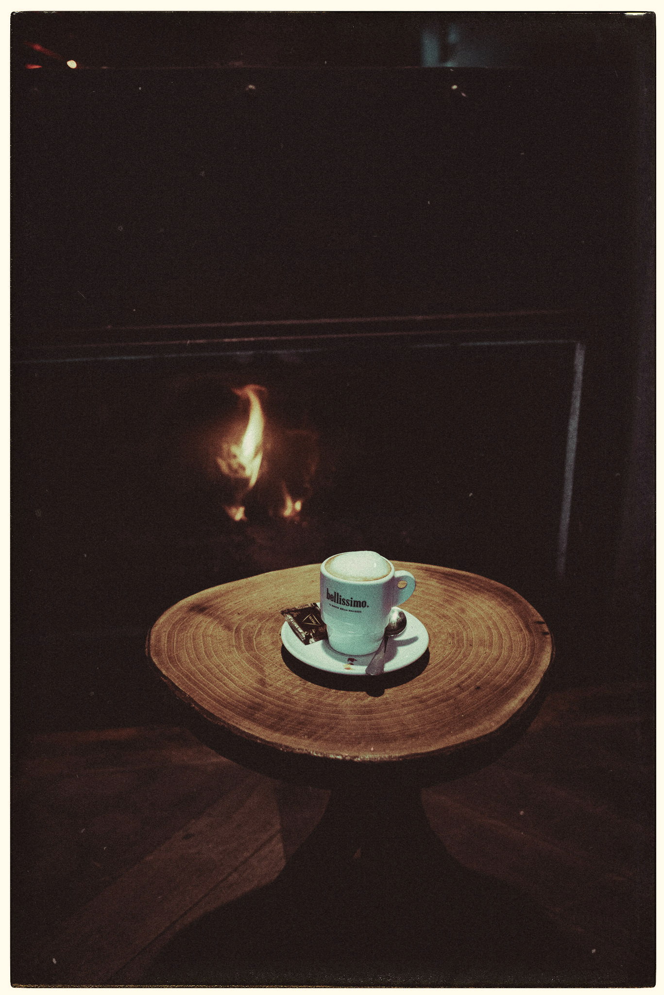 A coffee on a wood slice by an open fire, by Igor Świeczak