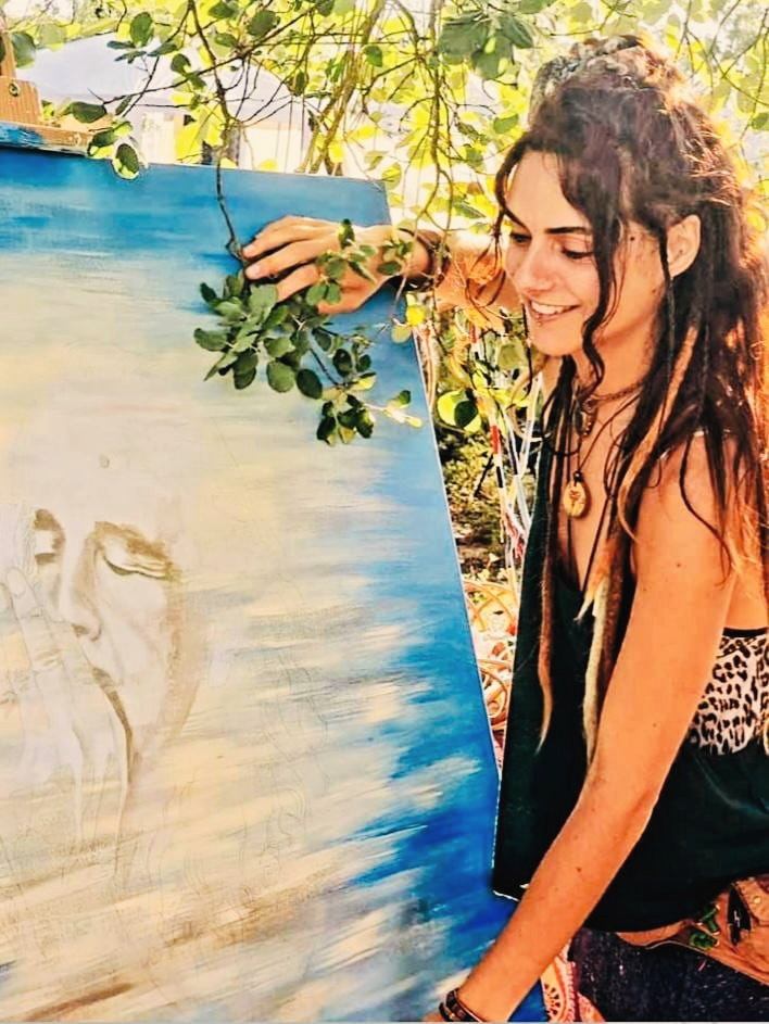 Lucia Maria at work on a large painting, outdoors under the trees
